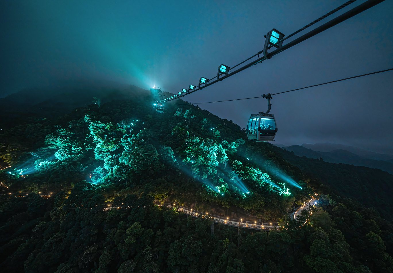 山地索道沿线夜间的青色洗树灯与缆绳